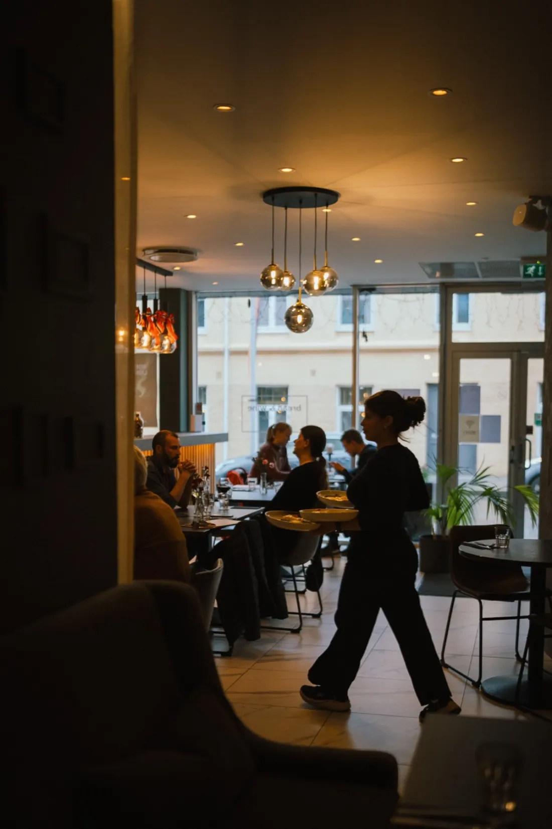 A waiter carrying plates through service at Bread & Wine